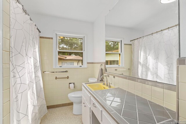 bathroom featuring tile walls, toilet, vanity, tile patterned flooring, and backsplash