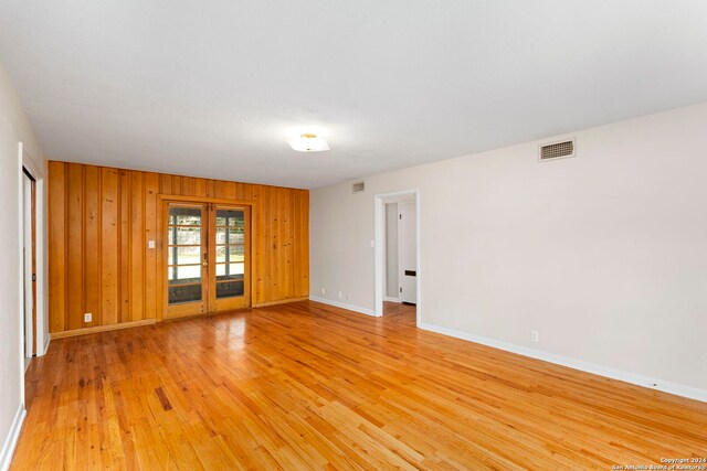 spare room featuring wood walls and light hardwood / wood-style floors