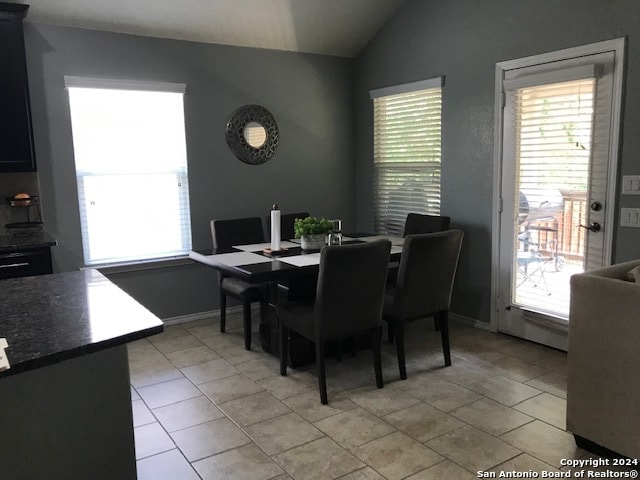 dining room featuring lofted ceiling and light tile patterned flooring