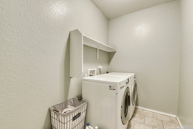 laundry area with light tile patterned flooring, a textured ceiling, and washing machine and dryer