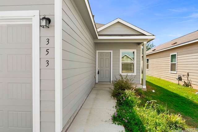 entrance to property featuring a yard and a garage