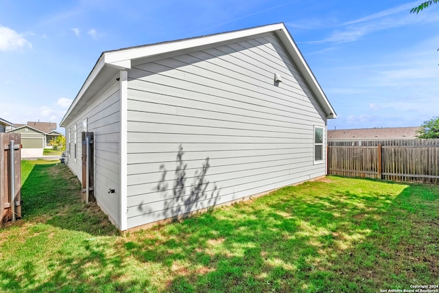 view of side of property featuring a lawn and fence