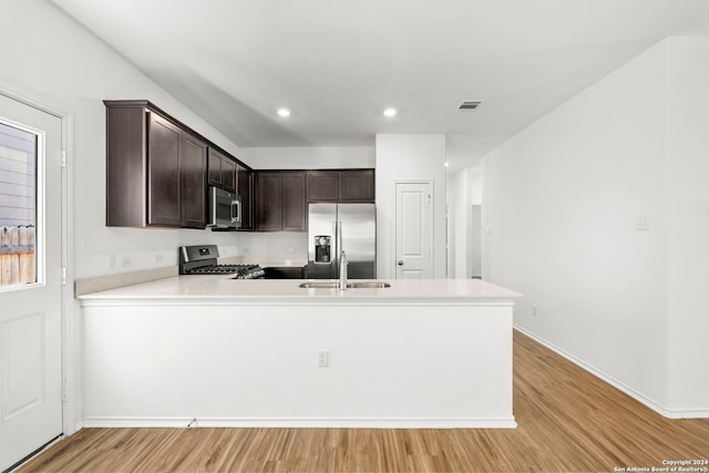 kitchen with visible vents, appliances with stainless steel finishes, a sink, dark brown cabinetry, and a peninsula