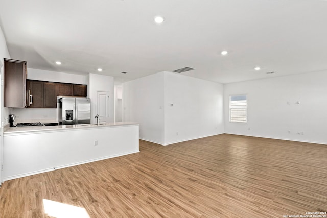 kitchen featuring dark brown cabinetry, stainless steel appliances, visible vents, open floor plan, and light wood finished floors