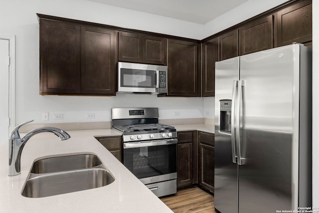 kitchen featuring appliances with stainless steel finishes, light countertops, a sink, and dark brown cabinets