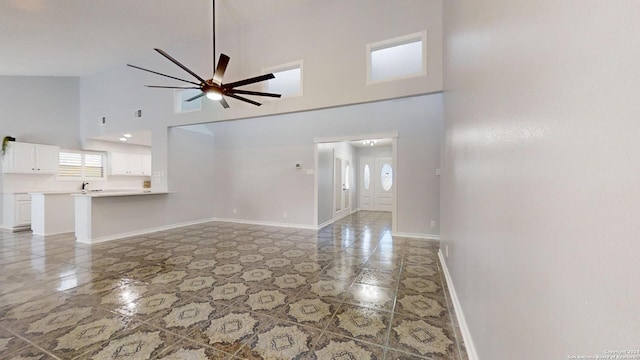 unfurnished living room featuring ceiling fan and high vaulted ceiling