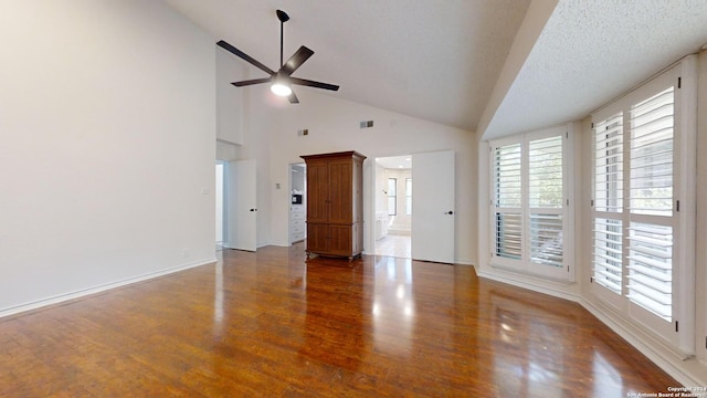 unfurnished living room with high vaulted ceiling, ceiling fan, a textured ceiling, and dark wood-type flooring