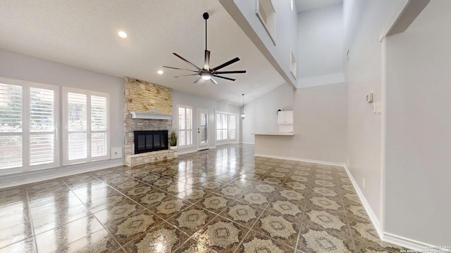 unfurnished living room with high vaulted ceiling, a fireplace, a textured ceiling, ceiling fan, and tile patterned floors