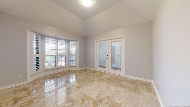 spare room featuring a textured ceiling, lofted ceiling, and french doors