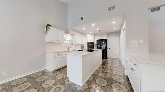 kitchen featuring a center island, sink, white cabinetry, black appliances, and a high ceiling