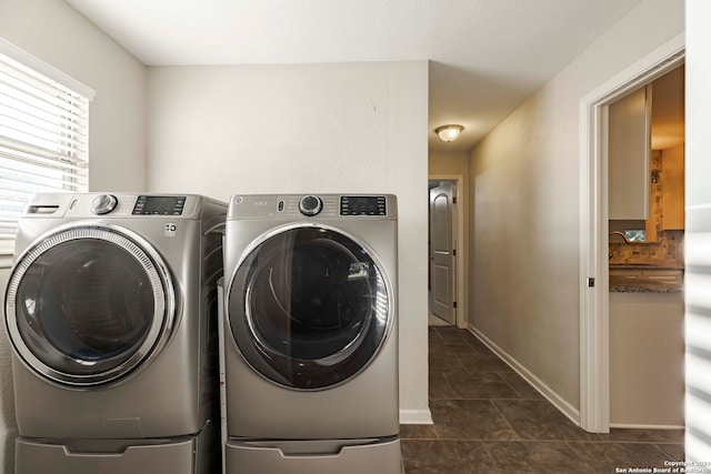 laundry area featuring washing machine and clothes dryer and dark tile patterned floors