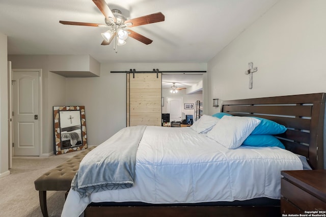 carpeted bedroom with a barn door and ceiling fan