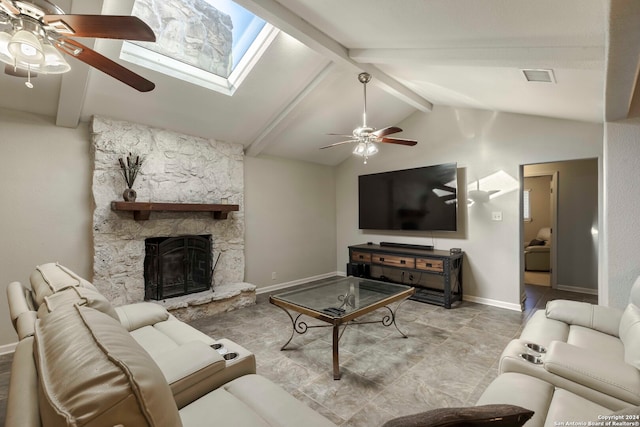 tiled living room featuring a stone fireplace, ceiling fan, and lofted ceiling with skylight