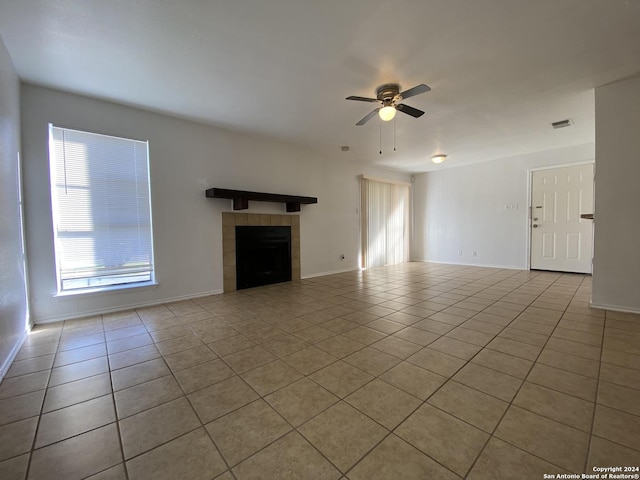 unfurnished living room with a tile fireplace, light tile patterned floors, and ceiling fan