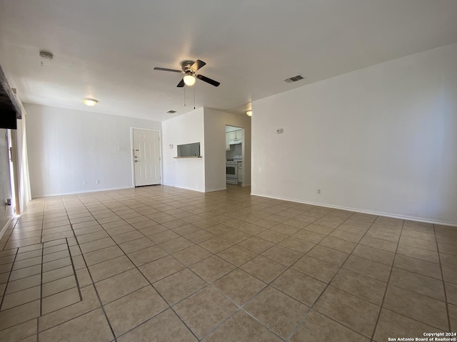 tiled empty room featuring visible vents, baseboards, and a ceiling fan