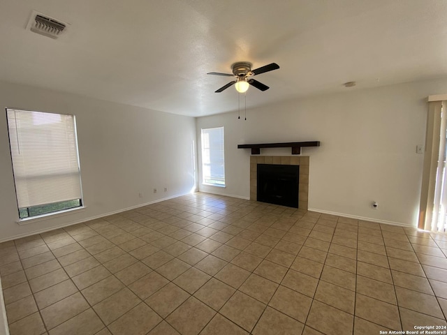 unfurnished living room with visible vents, baseboards, light tile patterned floors, a tile fireplace, and a ceiling fan