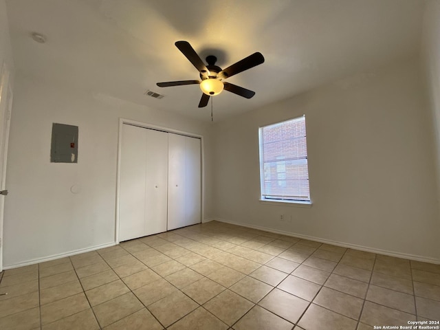 unfurnished bedroom featuring baseboards, visible vents, electric panel, light tile patterned flooring, and a closet