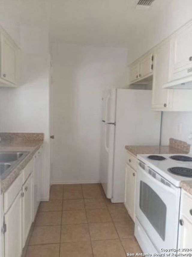 kitchen featuring white cabinets, white range with electric stovetop, light tile patterned floors, and extractor fan