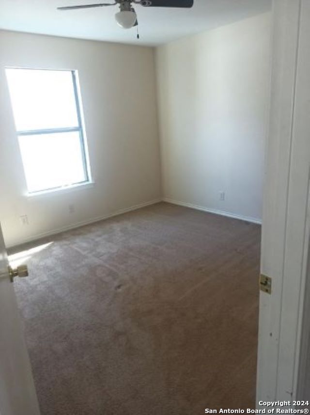 spare room with ceiling fan and dark carpet