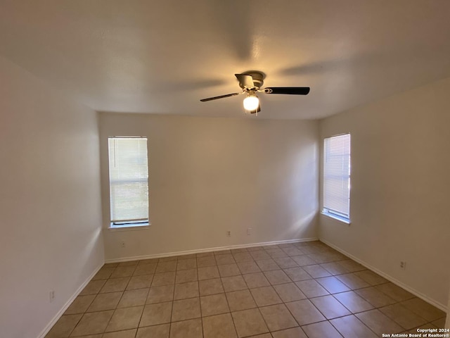 empty room with light tile patterned flooring, baseboards, and ceiling fan