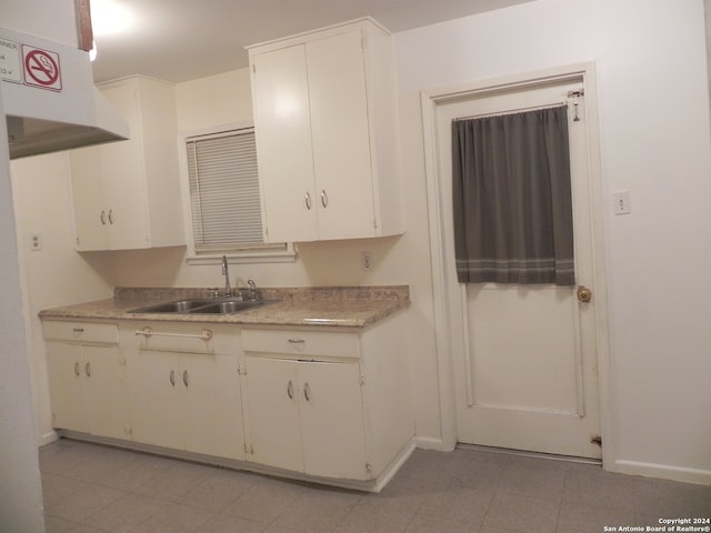 kitchen with white cabinets, sink, light tile patterned floors, and wall chimney exhaust hood