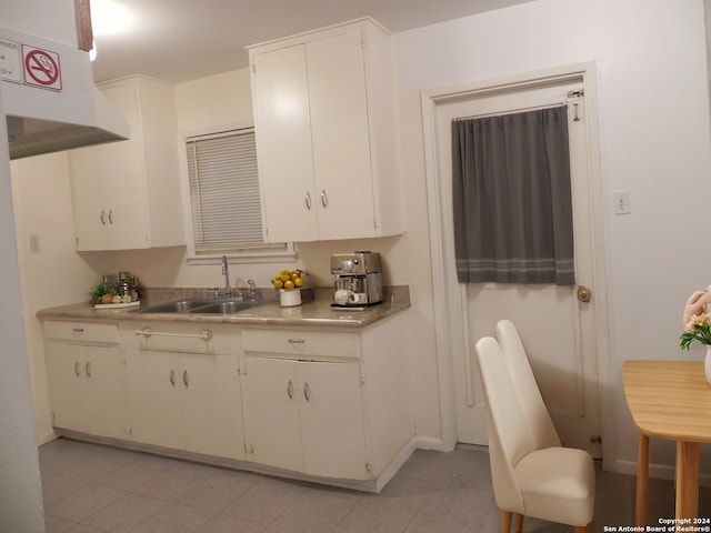 kitchen with light countertops, a sink, white cabinetry, and under cabinet range hood