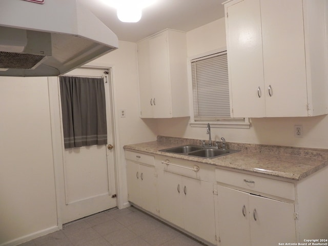 kitchen with light tile patterned flooring, island range hood, sink, and white cabinetry