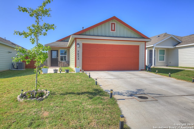 view of front of home featuring a garage, cooling unit, and a front lawn