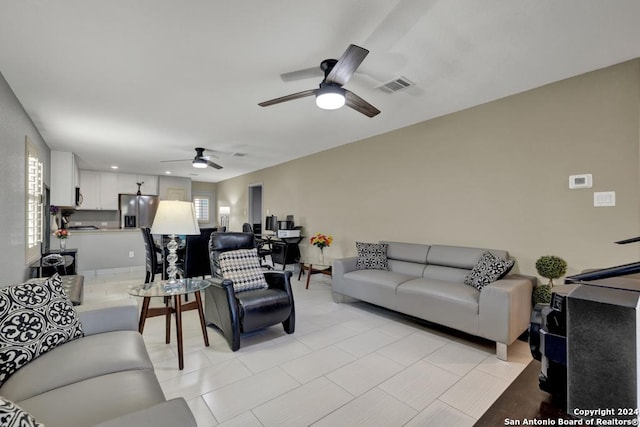 living room with light tile patterned floors, visible vents, and a ceiling fan