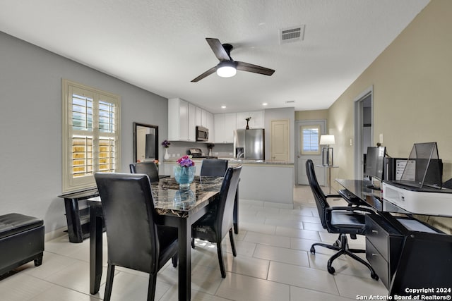 dining room with ceiling fan, plenty of natural light, a textured ceiling, and light tile patterned floors