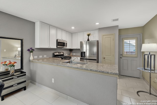 kitchen with white cabinets, stainless steel appliances, kitchen peninsula, and light tile patterned floors