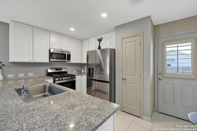 kitchen featuring light tile patterned floors, a sink, visible vents, white cabinetry, and appliances with stainless steel finishes