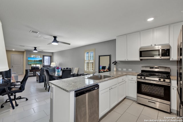 kitchen with appliances with stainless steel finishes, light stone countertops, ceiling fan, sink, and kitchen peninsula