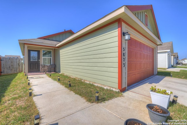 view of front of home with concrete driveway, an attached garage, and fence