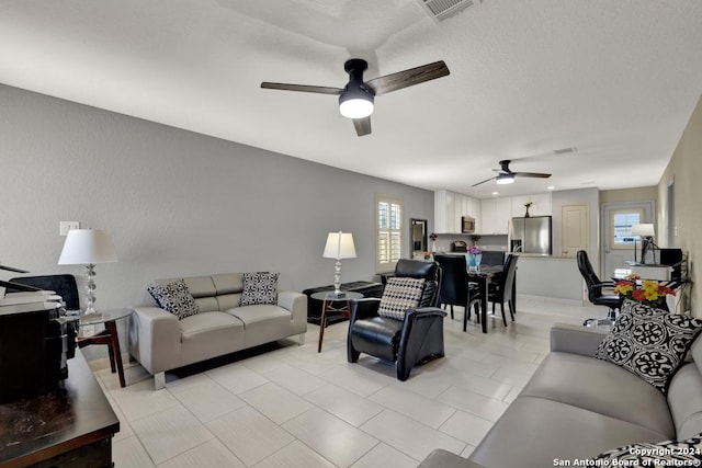 living room with light tile patterned floors, ceiling fan, visible vents, and a wealth of natural light