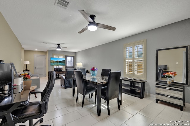 tiled dining space featuring ceiling fan and a textured ceiling