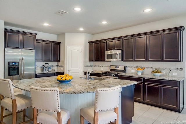 kitchen featuring appliances with stainless steel finishes, sink, a breakfast bar area, decorative backsplash, and a center island with sink