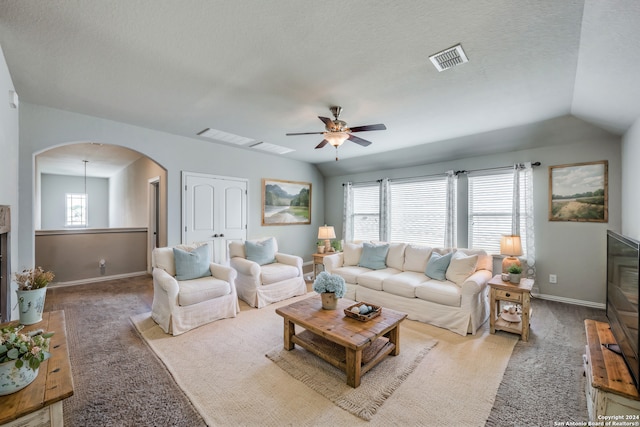 living room with ceiling fan, carpet flooring, vaulted ceiling, and a textured ceiling