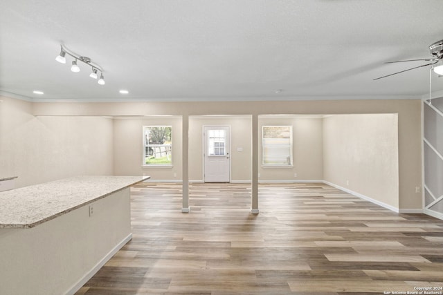 basement with baseboards, a ceiling fan, ornamental molding, a textured ceiling, and light wood-style floors