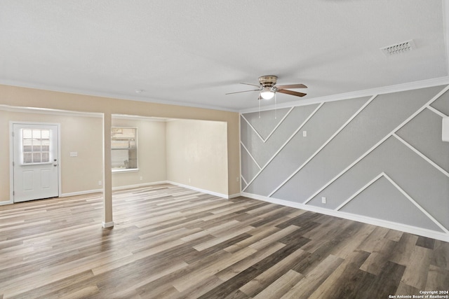 unfurnished living room with visible vents, ornamental molding, ceiling fan, wood finished floors, and baseboards