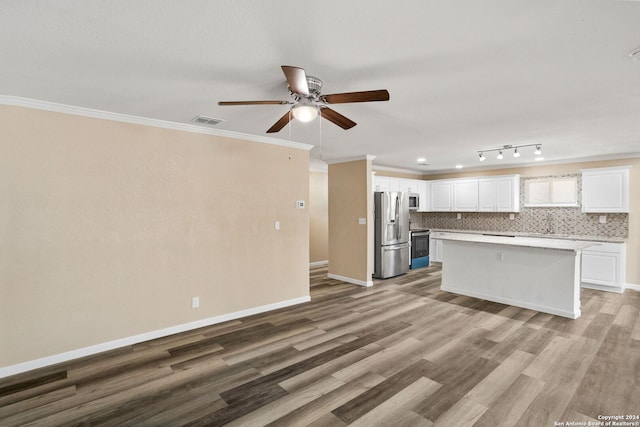 kitchen featuring visible vents, white cabinets, ornamental molding, tasteful backsplash, and stainless steel fridge