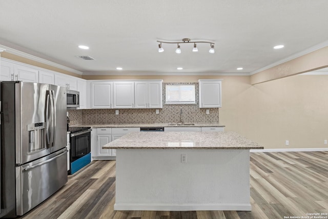 kitchen with a center island, crown molding, decorative backsplash, appliances with stainless steel finishes, and white cabinetry