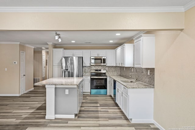 kitchen with a kitchen island, appliances with stainless steel finishes, ornamental molding, a sink, and backsplash