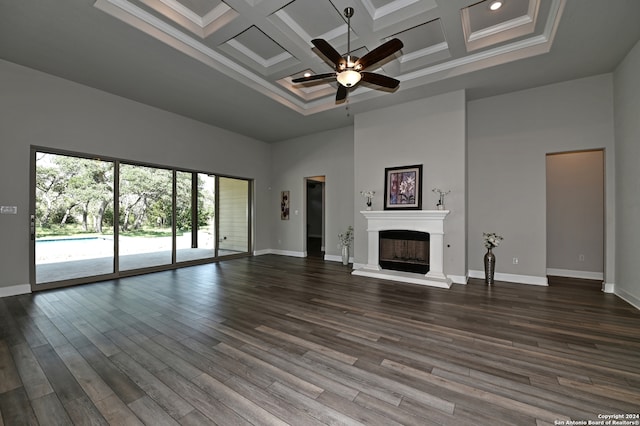 unfurnished living room with a towering ceiling, ceiling fan, coffered ceiling, hardwood / wood-style floors, and crown molding