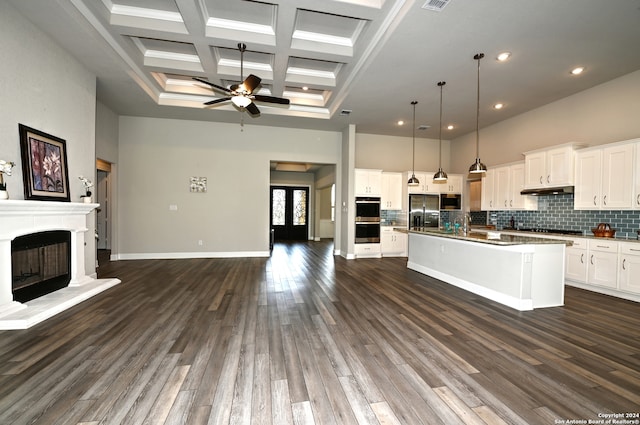 kitchen featuring coffered ceiling, dark hardwood / wood-style floors, an island with sink, ceiling fan, and beam ceiling