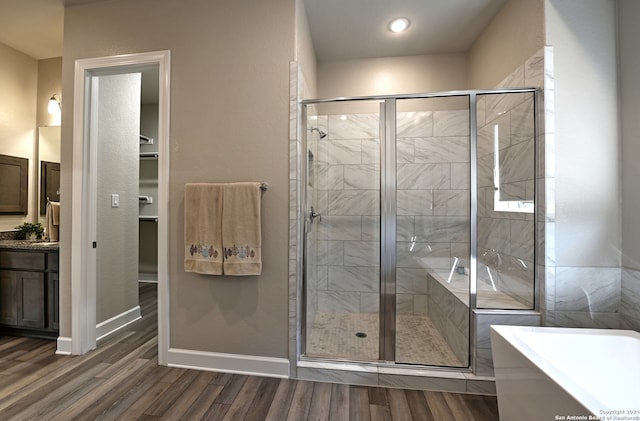 bathroom featuring vanity, wood-type flooring, and plus walk in shower