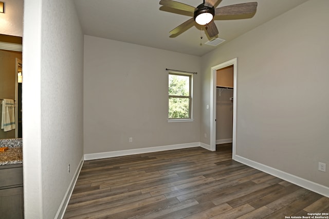 unfurnished bedroom with a closet, dark hardwood / wood-style floors, a spacious closet, and ceiling fan