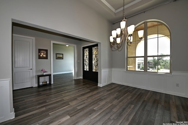 spare room with a notable chandelier, dark wood-type flooring, ornamental molding, and a tray ceiling