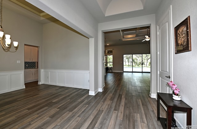 entrance foyer with ceiling fan with notable chandelier, dark hardwood / wood-style floors, a raised ceiling, beam ceiling, and coffered ceiling