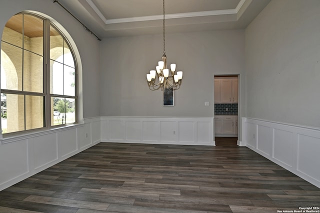 unfurnished dining area with a tray ceiling, a chandelier, and dark hardwood / wood-style flooring